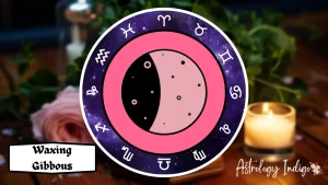 A symbol of a Waxing Gibbous Moon is surrounded by the Zodiac signs on a table with flowers and candles